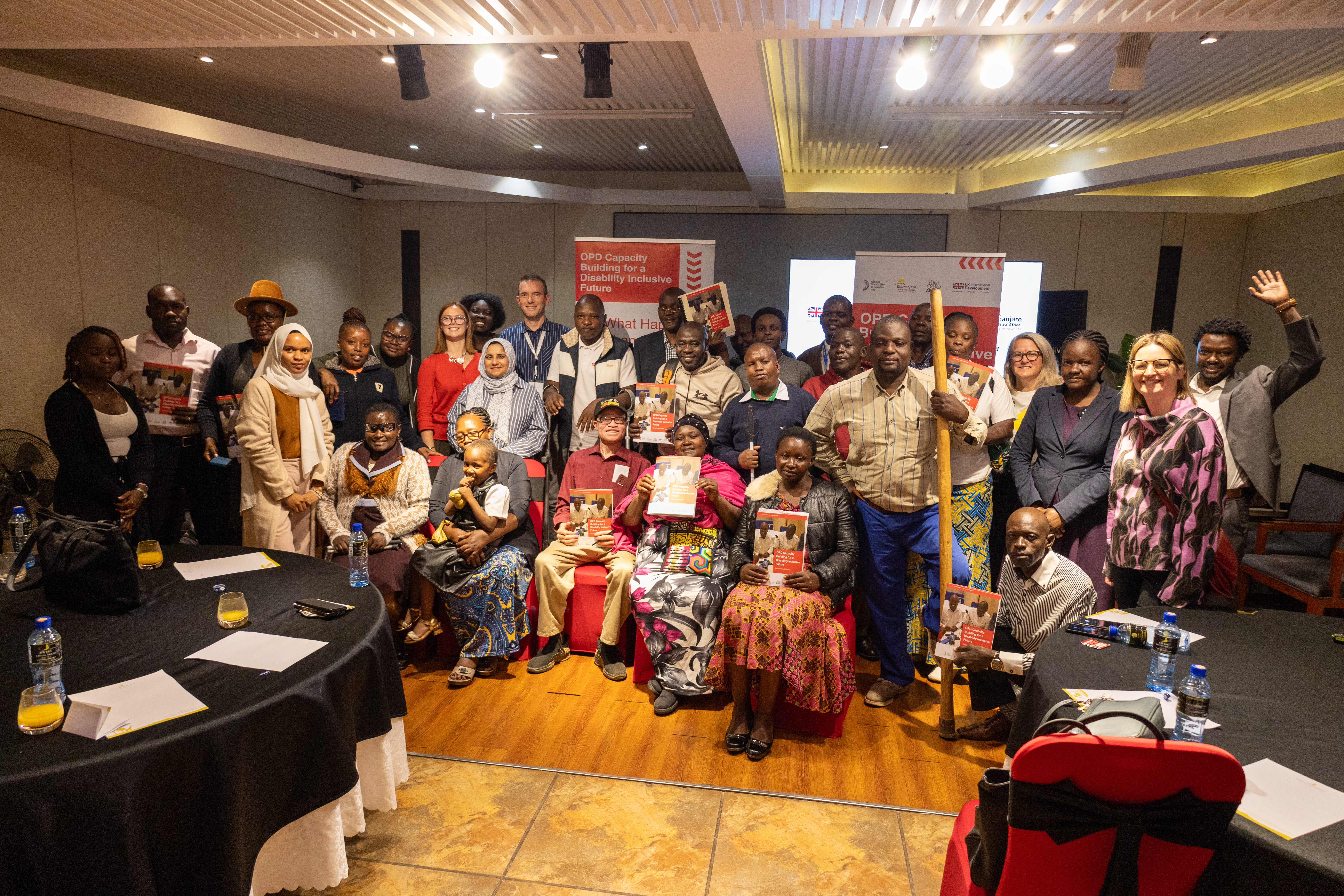 A diverse group of people standing in a conference hall in front of two posters with the letters OPD clearly visible